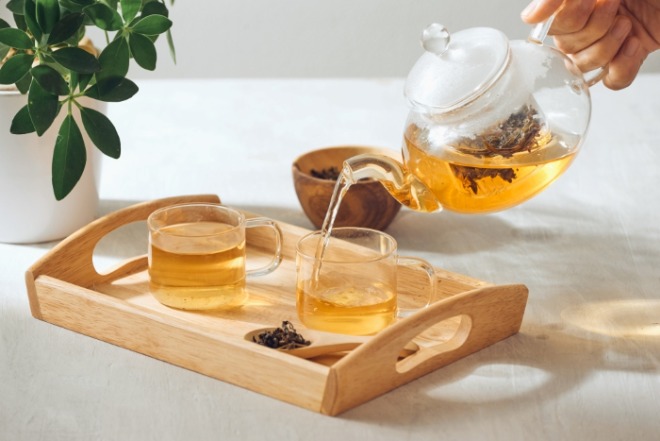 hand-pouring-tea-from-glass-teapot-wooden-serving-tray (1).jpg